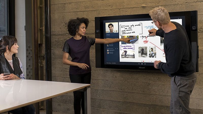 Een groep mensen videoconferenties houden op een groot scherm in een vergaderruimte.