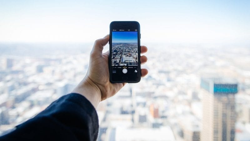 Een persoon die een mobiele telefoon vasthoudt met uitzicht op een Afrikaanse stad.