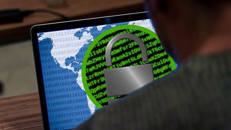 Een man kijkt naar een laptop met een hangslot erop, wat aangeeft dat Gemeente Hof van Twente slachtoffer is geworden van ransomware.